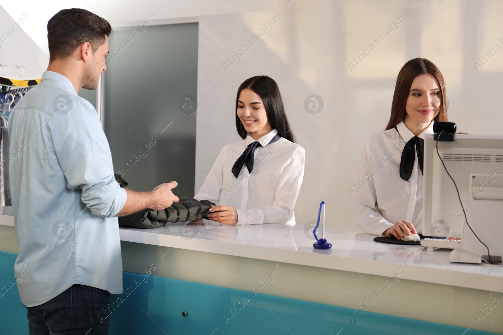 Photo of Female employees working with client at dry-cleaner's