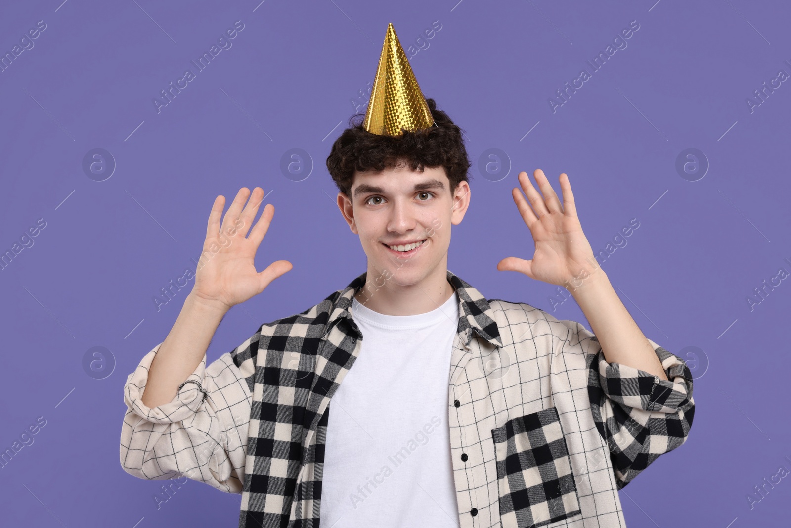 Photo of Young man in party hat on purple background