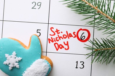 Photo of Gingerbread cookie and fir tree branch on calendar page with marked date, top view. December, 6 - Saint Nicholas Day