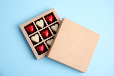 Photo of Tasty heart shaped chocolate candies on light blue background, flat lay. Happy Valentine's day