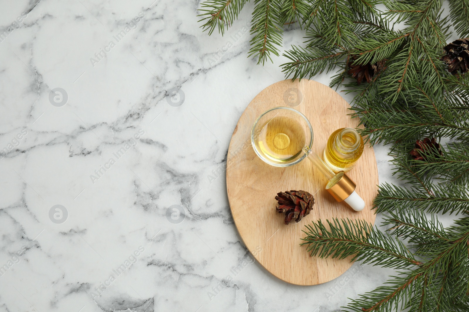 Photo of Pine essential oil, cones and branches on white marble table, flat lay. Space for text