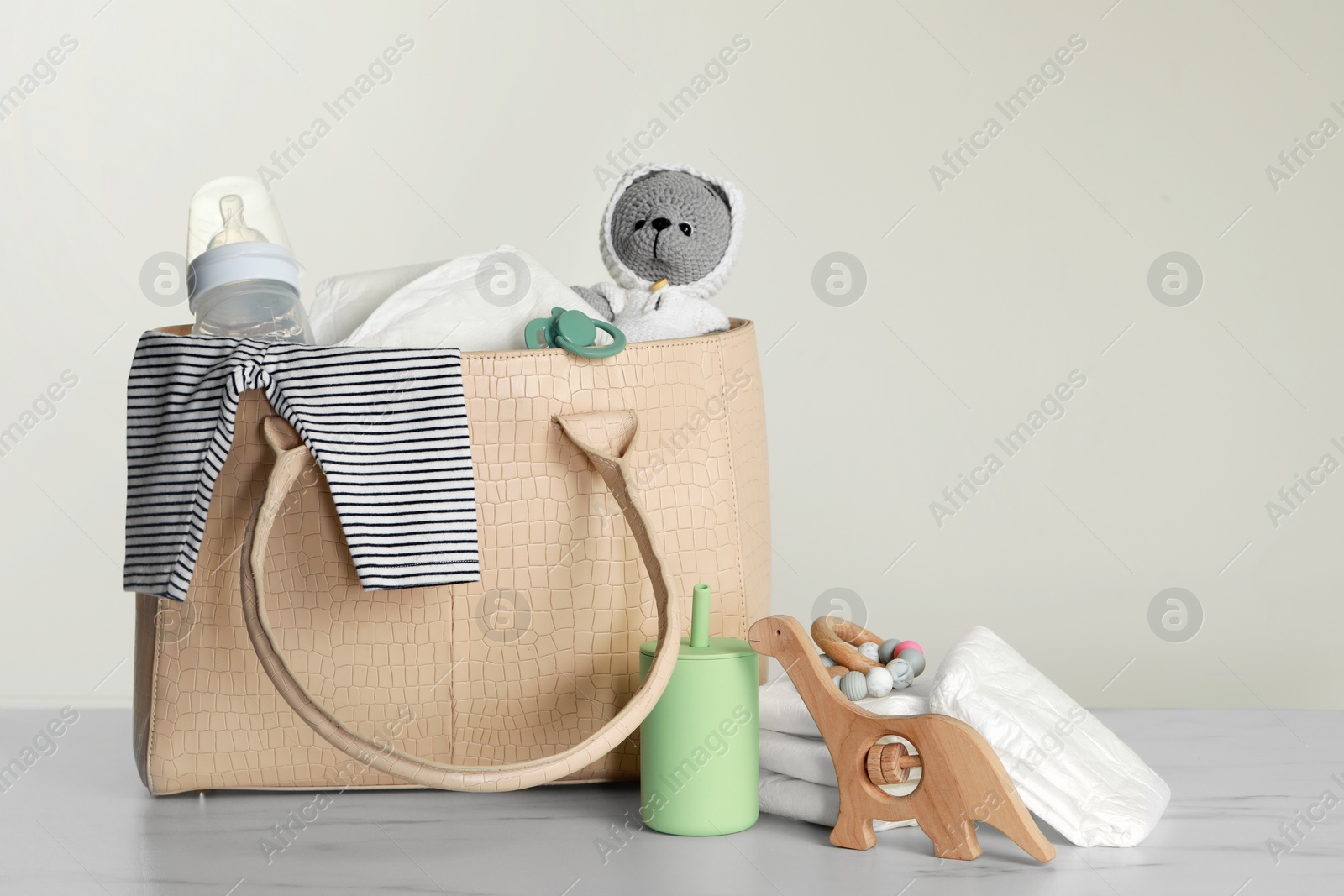 Photo of Mother's bag with baby's stuff on light grey background