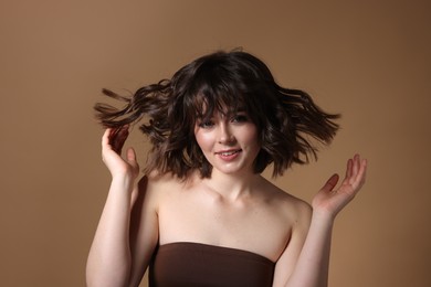 Photo of Portrait of beautiful young woman with wavy hairstyle on brown background