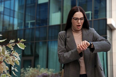 Emotional woman checking time on watch outdoors. Being late concept