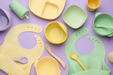 Photo of Flat lay composition with baby feeding accessories and bibs on violet background