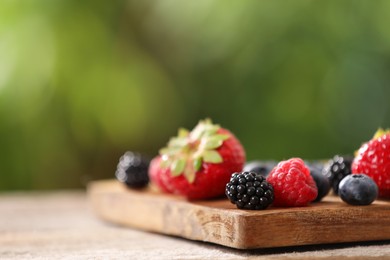 Photo of Different fresh ripe berries on wooden table outdoors, closeup. Space for text