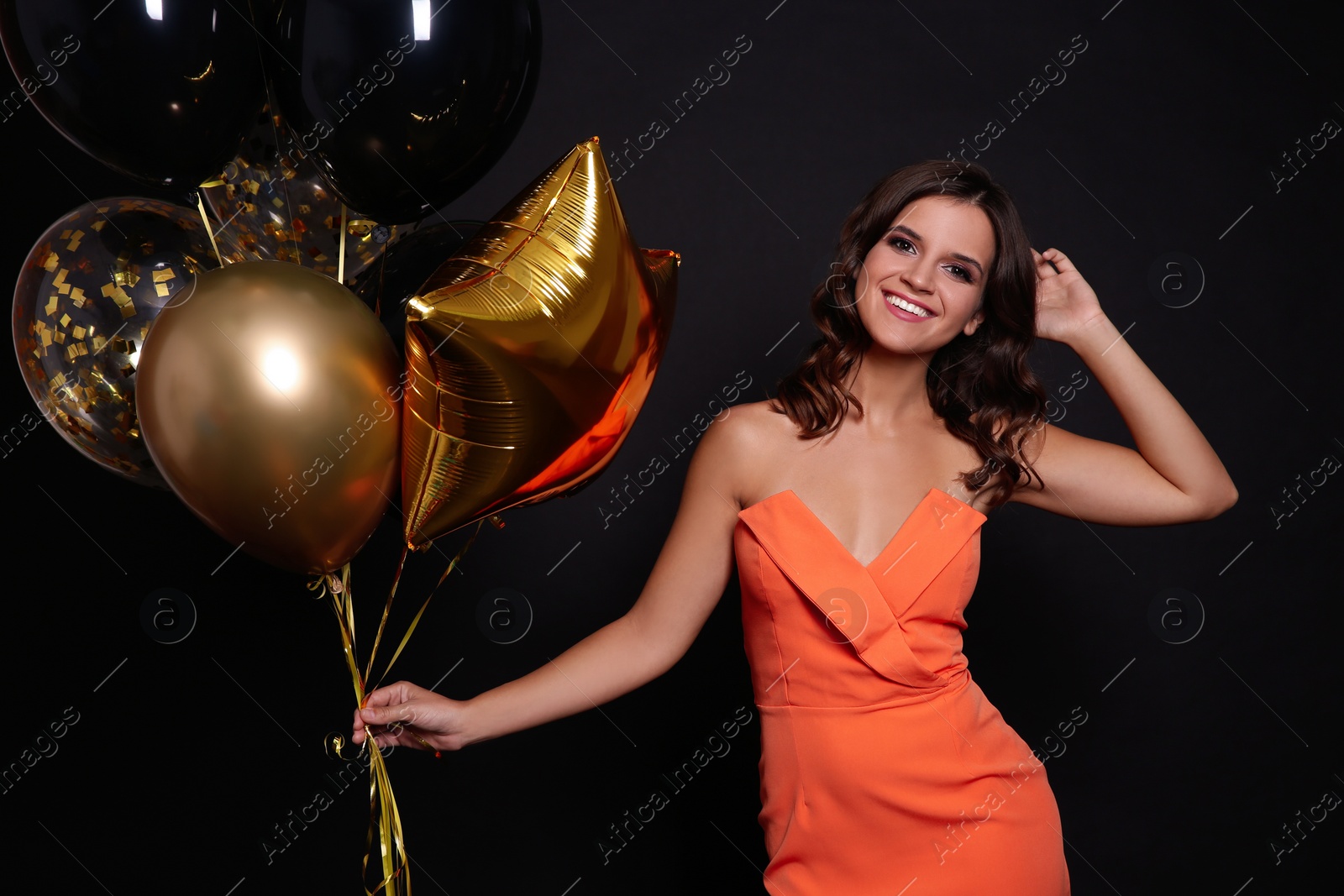 Photo of Happy woman with air balloons on black background. Christmas party