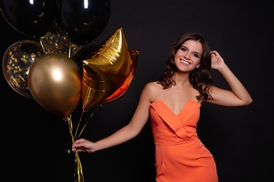 Happy woman with air balloons on black background. Christmas party