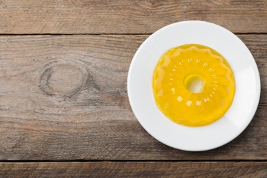 Photo of Delicious fresh yellow jelly on wooden table, top view. Space for text