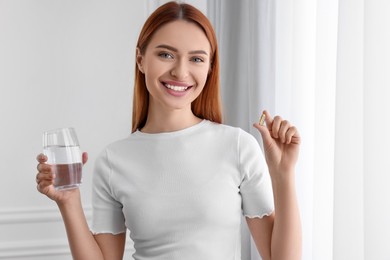 Photo of Beautiful young woman with vitamin pill and glass of water