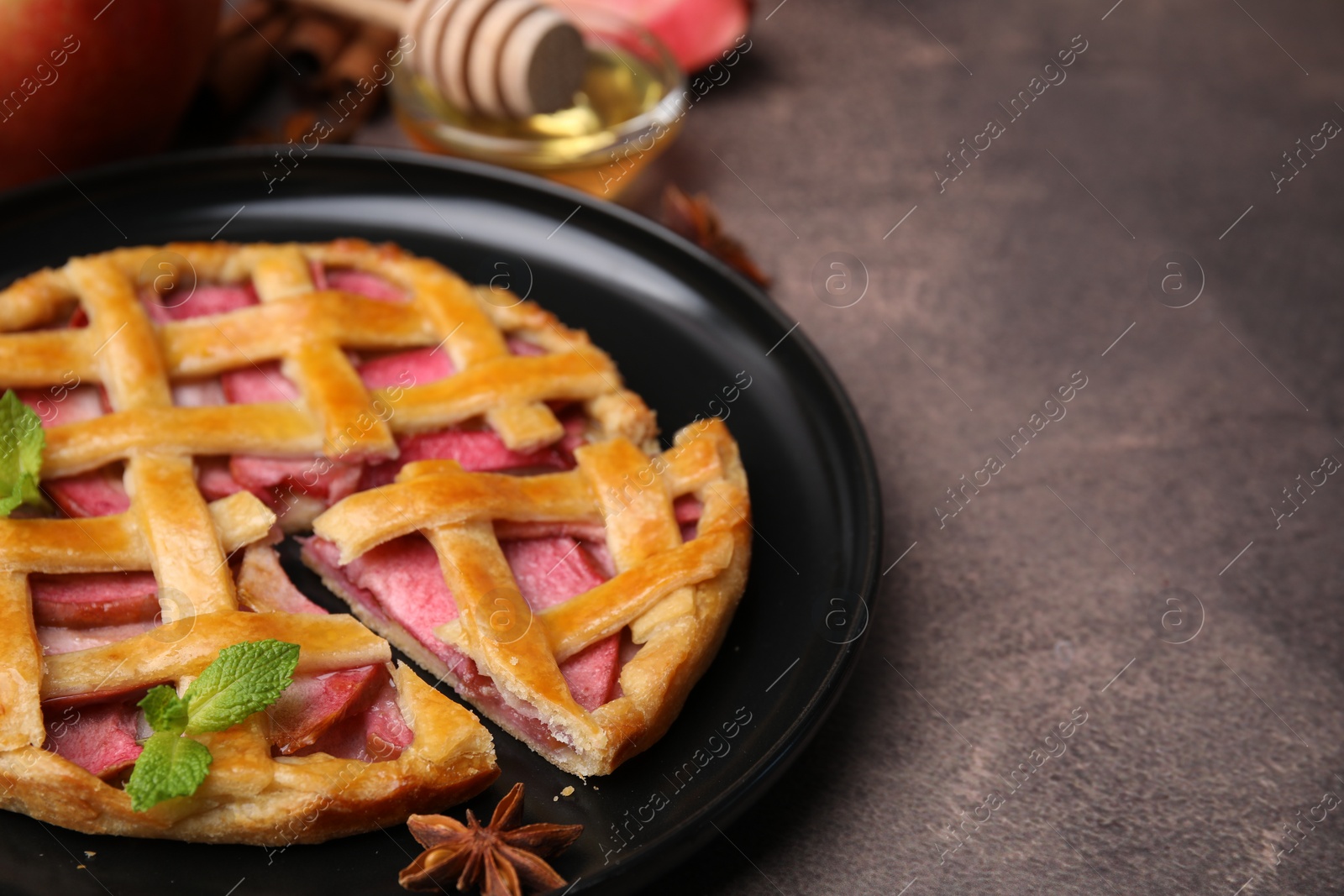 Photo of Delicious apple pie with mint on brown table, closeup. Space for text