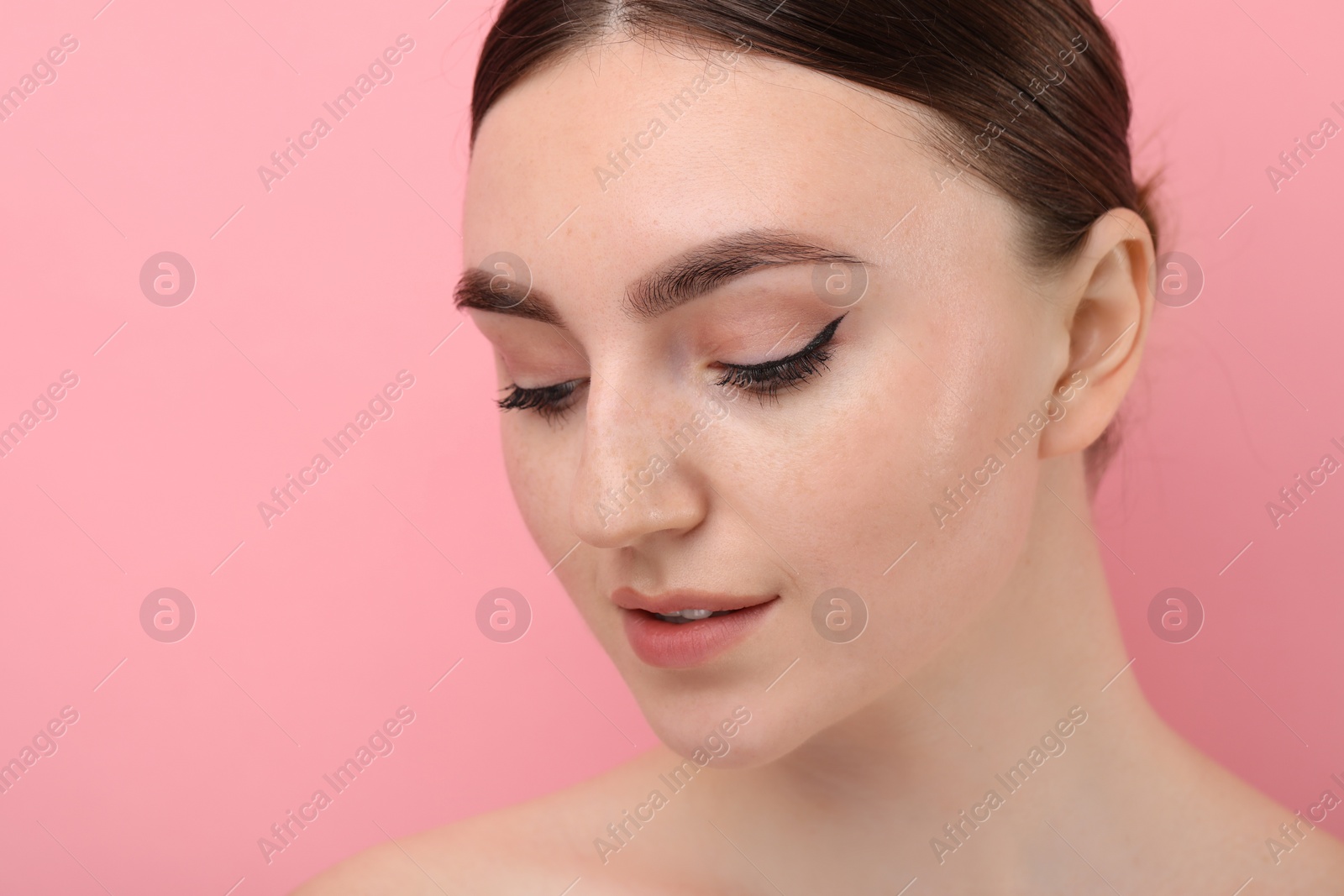 Photo of Makeup product. Woman with black eyeliner and beautiful eyebrows on pink background, closeup