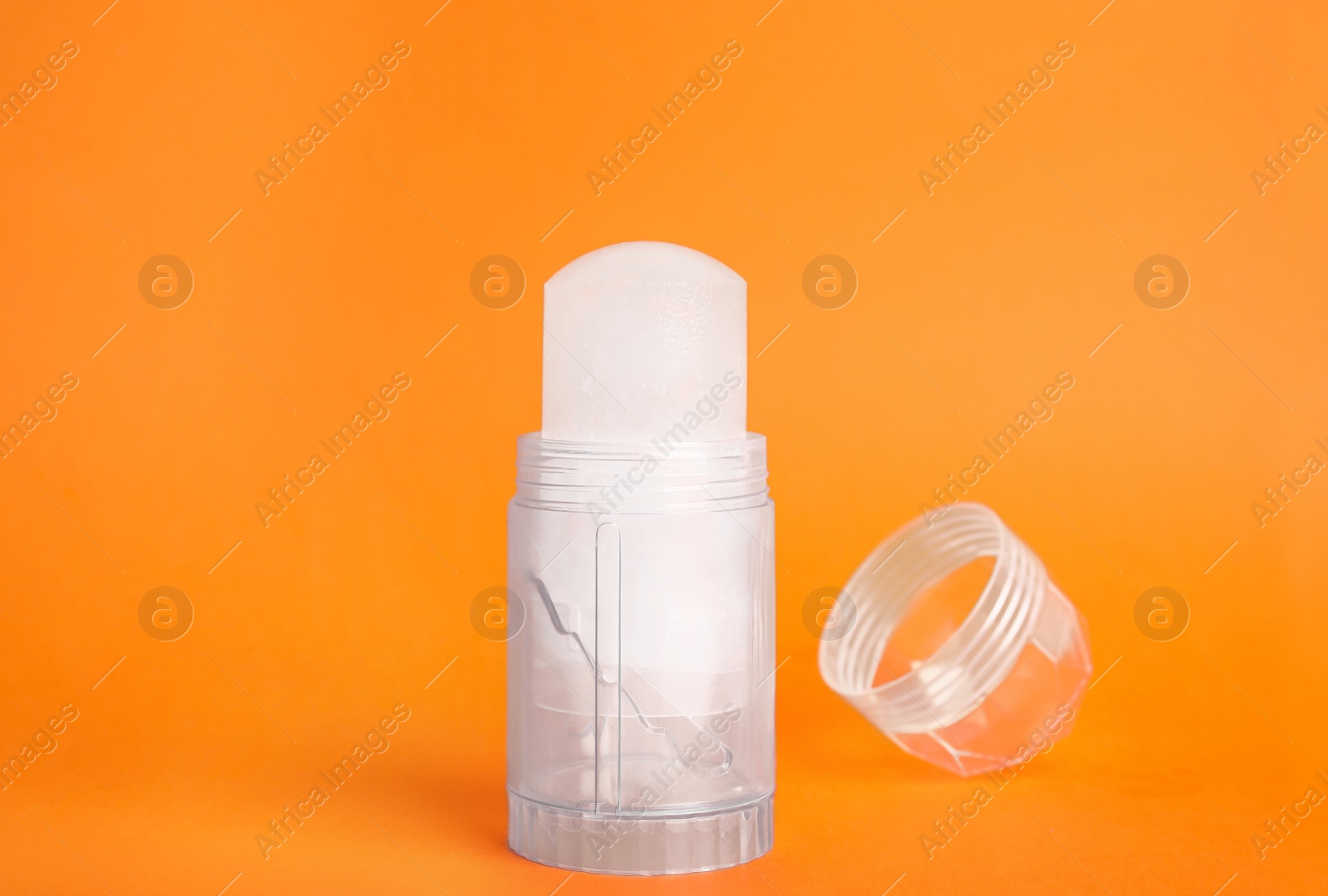 Photo of Natural crystal alum stick deodorant and cap on orange background