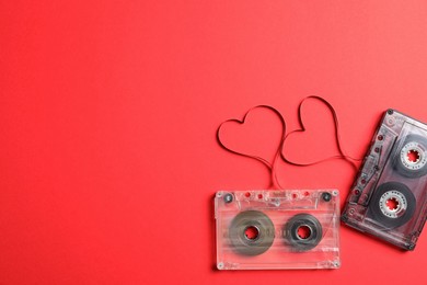 Photo of Music cassettes and hearts made of tape on red background, flat lay with space for text. Listening love songs