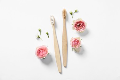 Photo of Flat lay composition with toothbrushes and flowers on white background