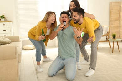 Happy friends singing karaoke together at home