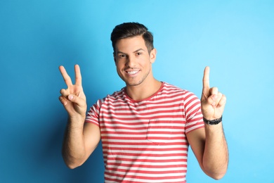 Photo of Man showing number three with his hands on light blue background