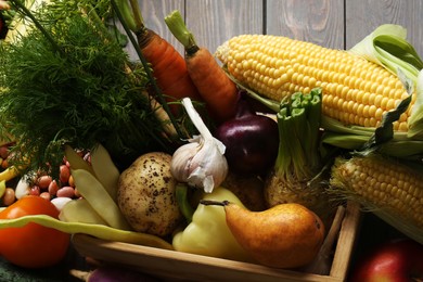 Different fresh vegetables with crate on wooden table, closeup. Farmer harvesting