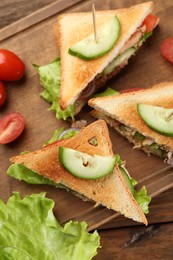 Photo of Delicious sandwiches with tuna and vegetables on wooden table, flat lay
