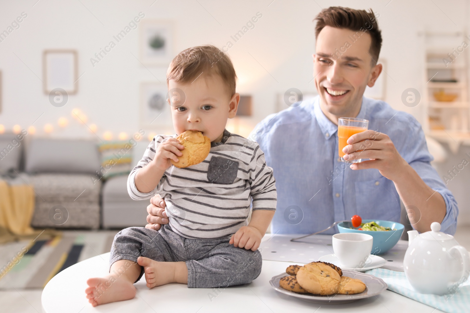 Photo of Young father with his cute little son eating in kitchen