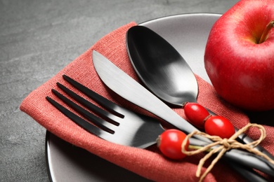 Photo of Festive table setting with rosehip berries and apple on black background, closeup. Thanksgiving Day celebration