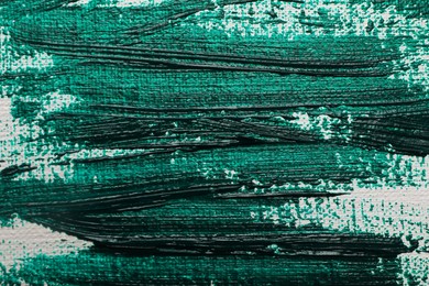 Photo of Strokes of green acrylic paint on white canvas, closeup