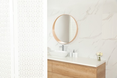 Photo of Modern bathroom interior with folding screen and round mirror