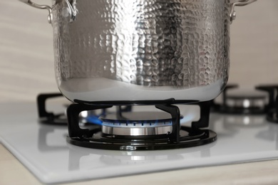 Photo of Shiny steel saucepan on modern gas stove, closeup