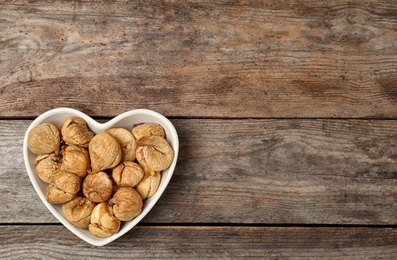 Photo of Bowl full of figs on wooden background, top view with space for text. Dried fruit as healthy food