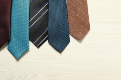 Photo of Different neckties on white wooden table, flat lay. Space for text