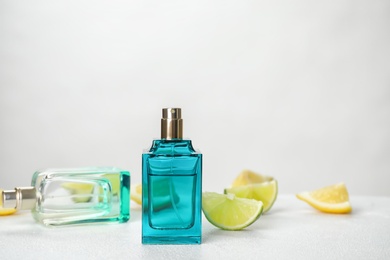 Perfume bottles and slices of citrus fruits on table against light background