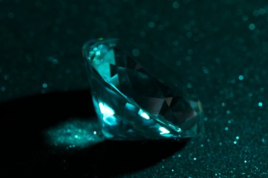 Beautiful dazzling diamond on green glitter surface, closeup