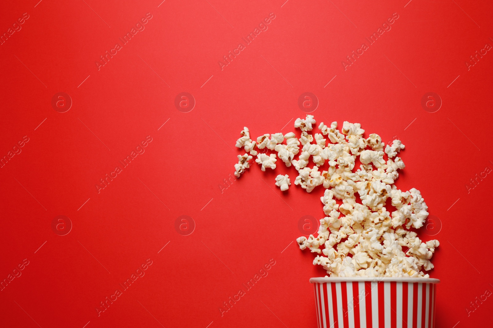 Photo of Delicious popcorn on red background, top view. Space for text