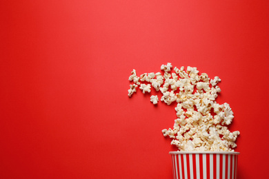 Photo of Delicious popcorn on red background, top view. Space for text