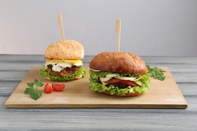 Photo of Delicious vegetarian burgers served on grey wooden table