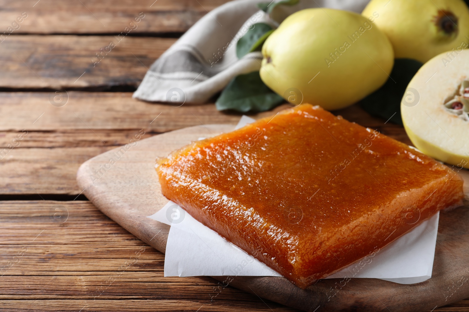 Photo of Delicious quince paste on wooden table, closeup. Space for text