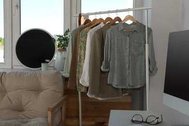 Photo of Rack with stylish clothes near window indoors. Interior design