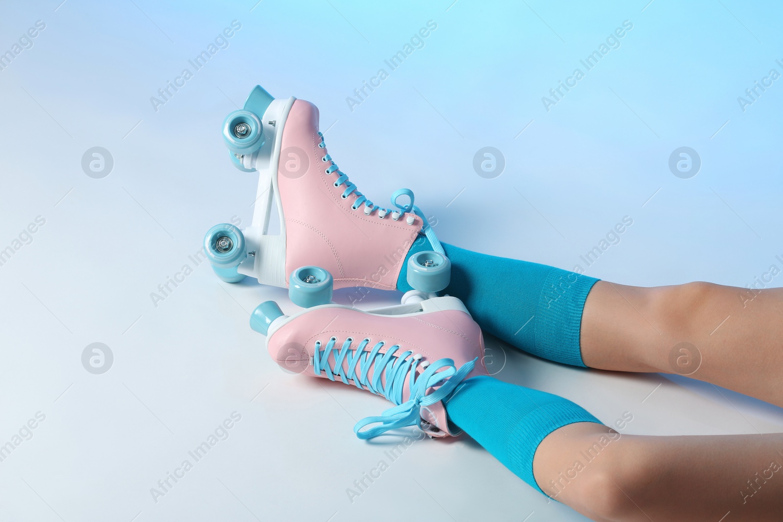 Photo of Woman with vintage roller skates on color background, closeup