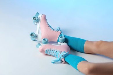 Photo of Woman with vintage roller skates on color background, closeup