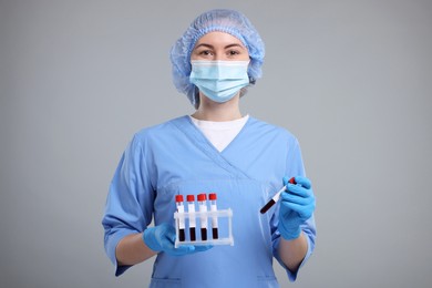 Laboratory testing. Doctor with blood samples in tubes on light grey background