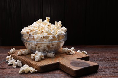Photo of Bowl of tasty popcorn on wooden table, space for text