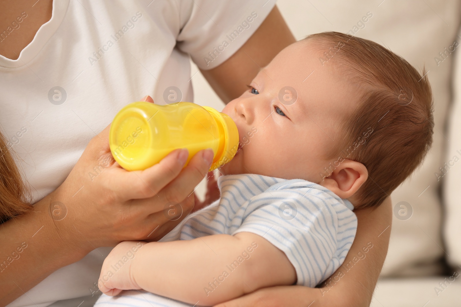 Photo of Mother feeding her cute child with infant formula indoors