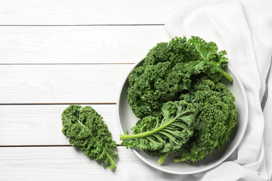 Photo of Fresh kale leaves on white wooden table, flat lay. Space for text