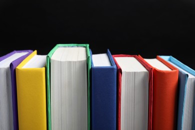 Different hardcover books on black background, closeup