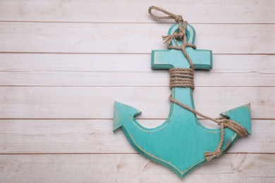 Anchor with hemp rope on wooden table, top view. Space for text