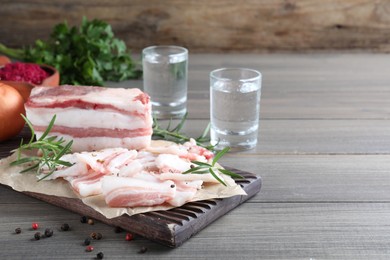 Photo of Tasty salt pork with rosemary and pepper on wooden table, space for text