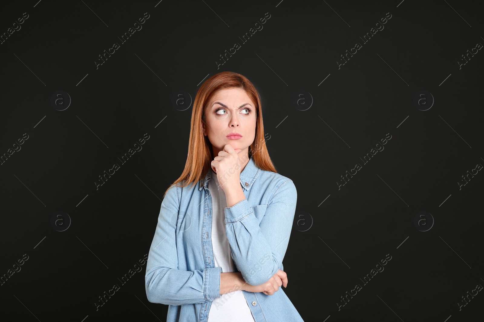Photo of Pensive woman on black background. Thinking about answer for question