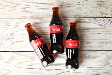 Photo of MYKOLAIV, UKRAINE - NOVEMBER 15, 2018: Bottles of Coca Cola on wooden background, top view