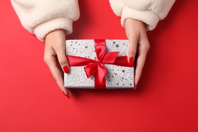 Photo of Christmas present. Woman with gift box on red background, top view