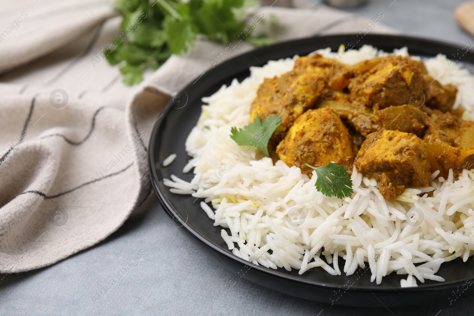 Photo of Delicious chicken curry with rice on grey table, closeup